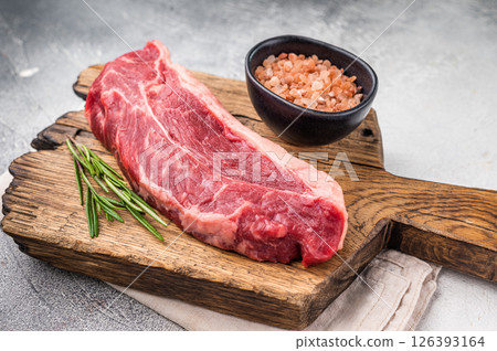 Uncooked striploin steak or strip New York on a wooden cutting board, inviting you to create mouthwatering recipes for any occasion. white background. top view 126393164