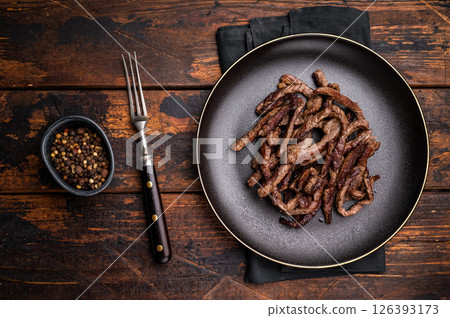 BBQ Fried beef tender strips, sliced steak in a plate. wooden background. top view BBQ Fried beef tender strips, sliced steak in a plate. wooden background. top view 126393173