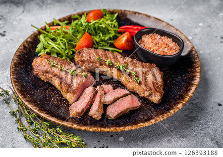 BBQ Grilled skirt or machete Steak, beef meat on a plate with salad. grey background. top view 126393188