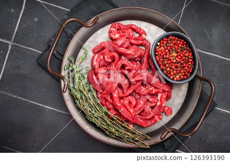 Beef sliced meat, raw veal strips for cooking beef stroganoff on a steel tray. black background. top view Beef sliced meat, raw veal strips for cooking beef stroganoff on a steel tray. black background. top view 126393190