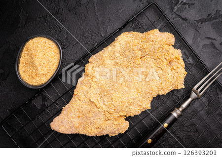 Raw breaded pork Schnitzel steak on a rack. black background. top view 126393201