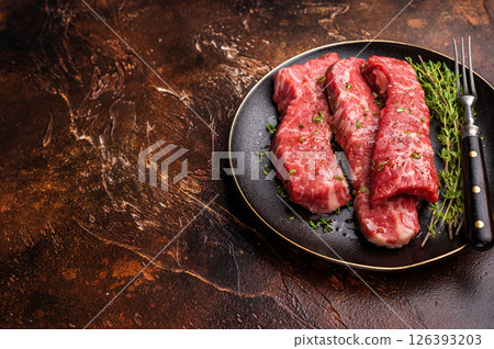 Tri tip steaks, Raw marbled beef meat on plate with herbs. brown background. top view 126393203