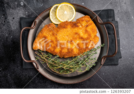 German Wiener schnitzel steak, breaded pork fillet meat. black background. top view German Wiener schnitzel steak, breaded pork fillet meat. black background. top view 126393207