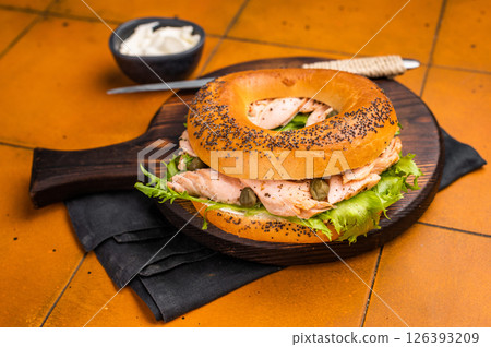 Breakfast Bagel with smoked salmon, lettuce and cream cheese on a wooden board. orange background. top view 126393209