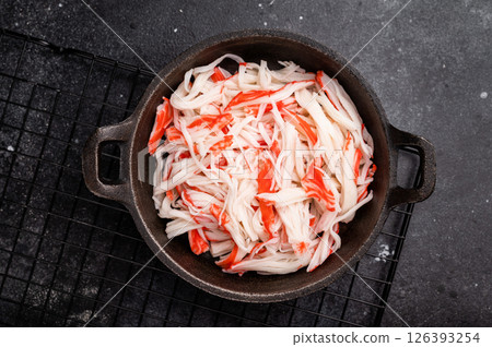 japanese Crab meat, crabmeat imitation in a skillet. black background. top view japanese Crab meat, crabmeat imitation in a skillet. black background. top view 126393254