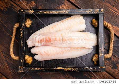 Fresh fish meat, Raw cod loin pieces without skin in wooden tray. wooden background. top view Fresh fish meat, Raw cod loin pieces without skin in wooden tray. wooden background. top view 126393255