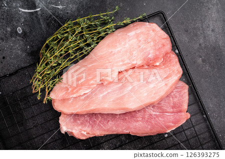 Raw pork fillet meat for schnitzel, steaks on a rack. black background. top view 126393275