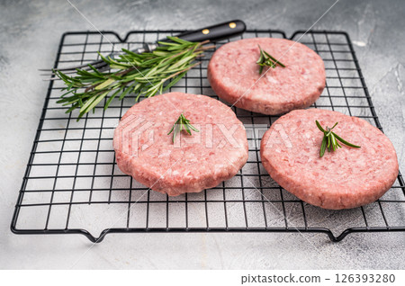 Close up of a juicy raw meat patty cutlet, ideal for crafting mouthwatering sandwiches and savory dishes. white background. top view 126393280