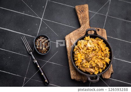 Pilaf with beef and lamb meat, vegetables in a skillet. black background. top view Pilaf with beef and lamb meat, vegetables in a skillet. black background. top view 126393288