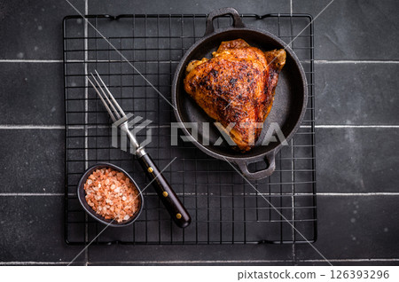 Fried roasted chicken thigh in a skillet, eco poultry meat. black background. top view Fried roasted chicken thigh in a skillet, eco poultry meat. black background. top view 126393296