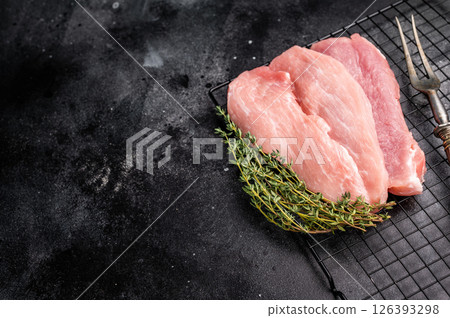 Raw pork fillet meat for schnitzel, steaks on a rack. black background. top view Raw pork fillet meat for schnitzel, steaks on a rack. black background. top view 126393298