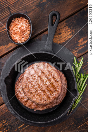 Deliciously charred grilled meat burger patty on the grill, perfect for satisfying cravings at any cookout. wooden background. top view Deliciously charred grilled meat burger patty on the grill, perfect for satisfying cravings at any cookout. wooden background. top view 126393316