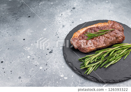 Close up of a flavorful grilled striploin or strip steak, garnished with herbs, ready to impress at your next dinner. grey background. top view 126393322