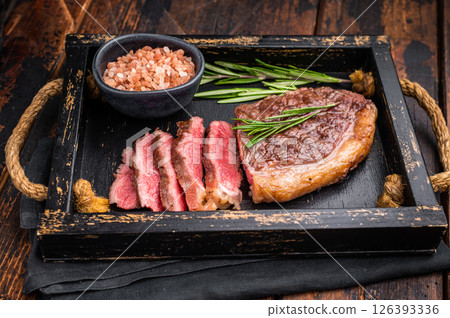 Deliciously charred grilled New York strip or striploin steak with rich marbling, an essential dish for any outdoor gathering. wooden background. top view 126393336