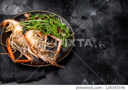 Elegant plate of grilled rosenbergii prawns shrimps garnished with fresh herbs, perfect for gourmet dining experiences. black background. top view 126393546
