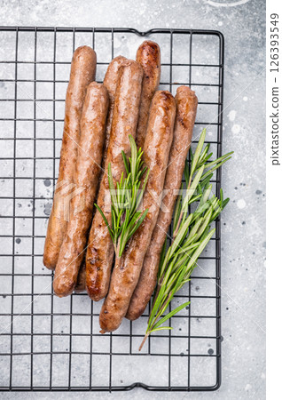 Flavorful grilled sausage links on a rack, inviting you to enjoy a hearty meal with family and friends. grey background. top view Flavorful grilled sausage links on a rack, inviting you to enjoy a hearty meal with family and friends. grey background. top view 126393549