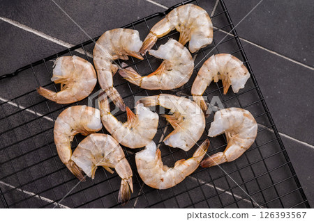 Raw shrimps, headless fresh prawns on a rack. Top view. Black background 126393567