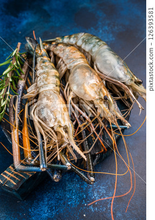Uncooked rosenbergii fresh water shrimp ready for preparation, perfect for chefs looking to create exquisite seafood dishes. blue background. top view Uncooked rosenbergii fresh water shrimp ready for preparation, perfect for chefs looking to create exquisite seafood dishes. blue background. top view 126393581