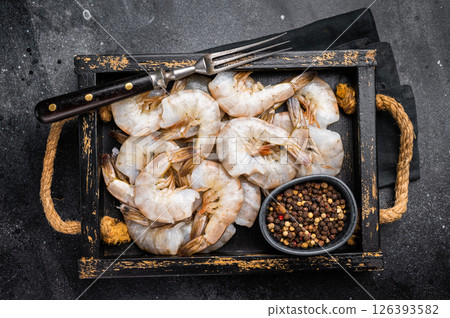 Fresh Raw headless tiger shrimps prawns in a tray. Top view. Black background Fresh Raw headless tiger shrimps prawns in a tray. Top view. Black background 126393582