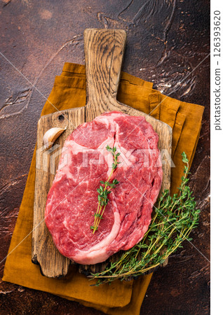 Fresh Marbled Rib eye steak with herbs on butcher cutting board, raw beef meat. brown background. top view Fresh Marbled Rib eye steak with herbs on butcher cutting board, raw beef meat. brown background. top view 126393620