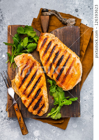 Chicken breasts steaks on cutting board, grilled poultry meat, top view, gray background. 126393623