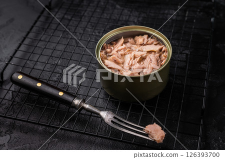Convenient tinned tuna fillet, perfect for quick meals and packed with protein for a healthy lifestyle. black background. top view Convenient tinned tuna fillet, perfect for quick meals and packed with protein for a healthy lifestyle. black background. top view 126393700