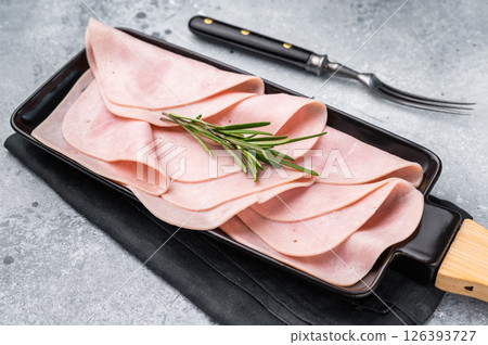 Gourmet sliced ham on a rustic board, inviting you to explore delicious recipes and delightful pairings. grey background. top view 126393727