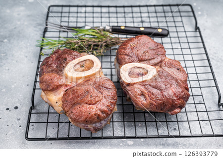 Tender veal osso buco, cross cut shank simmered in rich sauce, a timeless recipe that delights the senses and warms the heart. grey background. top view Tender veal osso buco, cross cut shank simmered in rich sauce, a timeless recipe that delights the senses and warms the heart. grey background. top view 126393779