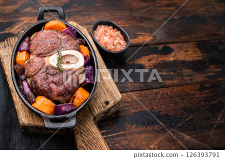 Hearty ossobuco slow cooked to perfection, showcasing succulent osso buco shank meat and aromatic herbs in a comforting stew. wooden background. top view Hearty ossobuco slow cooked to perfection, showcasing succulent osso buco shank meat and aromatic herbs in a comforting stew. wooden background. top view 126393791