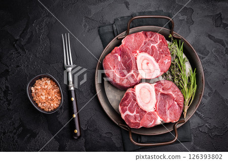 Freshly cross cut shank osso buco, ossobuco meat featuring succulent meat and bone marrow, waiting to elevate your cooking experience. black background. top view 126393802