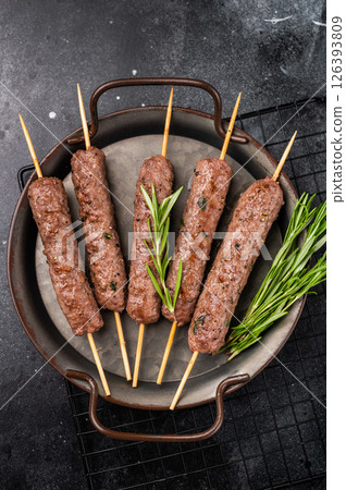 Grilled minced beef and lamb kebabs skewers with fresh spices, arabic kofta kofte kebab. black background. top view Grilled minced beef and lamb kebabs skewers with fresh spices, arabic kofta kofte kebab. black background. top view 126393809