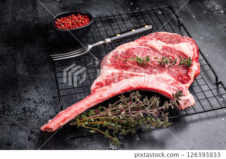 Uncooked tomahawk steak, raw black angus beef rib eye with bone. black background. top view 126393833