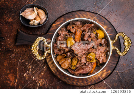Slow cooked Beef Cheek, Braised meat with vegetables in a skillet. brown background. top view 126393856