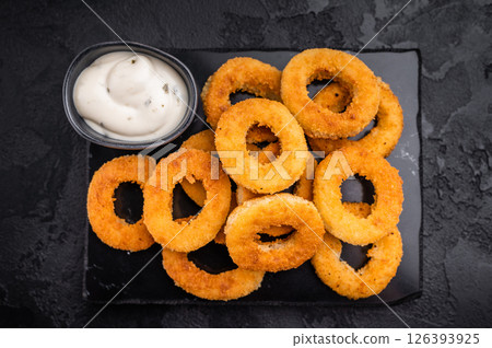 Deep fried squid rings with breading, calamari fastfood snack. black background. top view 126393925