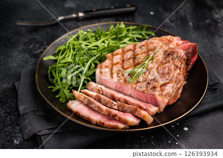 BBQ grilled pork tender steak, neck meat, on plate with salad. black background. top view BBQ grilled pork tender steak, neck meat, on plate with salad. black background. top view 126393934