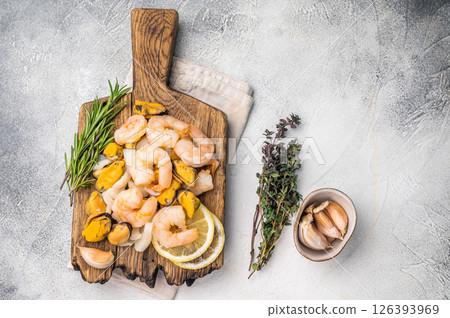 Fresh Seafood cocktail, raw Mix with Mussels, Clams, Prawns, Shrimps and squid on wooden board. white background. top view 126393969