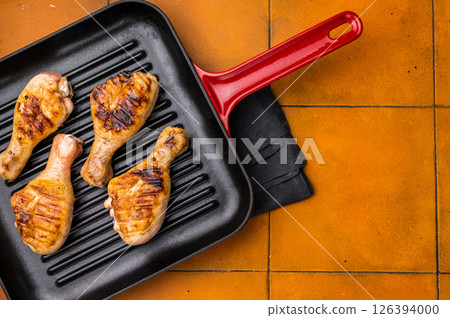 Succulent grilled drumsticks, marinated to perfection and served hot off the grill for a delightful dining experience. orange background. top view 126394000