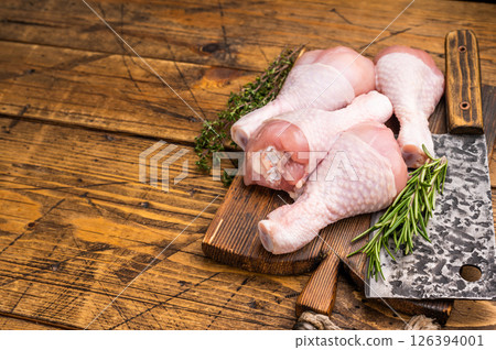 Pristine raw chicken drumsticks, leg quarters, ready to be transformed into a mouthwatering dish full of flavor. wooden background. top view 126394001