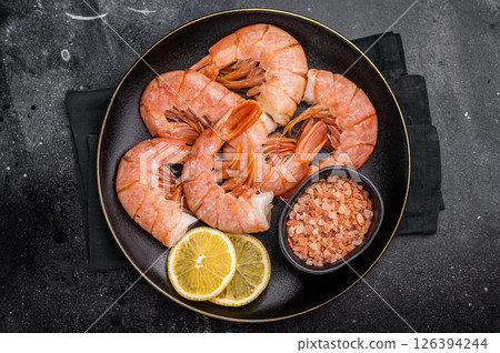 Uncooked Headless Red shrimps, raw Prawns on plate. black background. top view Uncooked Headless Red shrimps, raw Prawns on plate. black background. top view 126394244