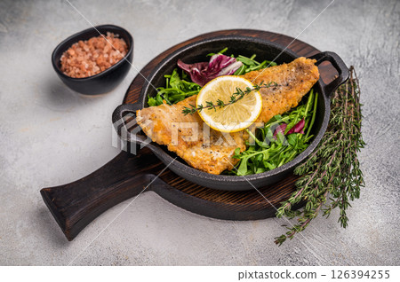 Fried Haddock fish fillet in a pan. grey background. top view Fried Haddock fish fillet in a pan. grey background. top view 126394255