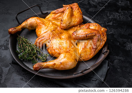Roasted chicken Tabaka with herbs and spices, poultry meat on steel tray. black background. top view Roasted chicken Tabaka with herbs and spices, poultry meat on steel tray. black background. top view 126394286