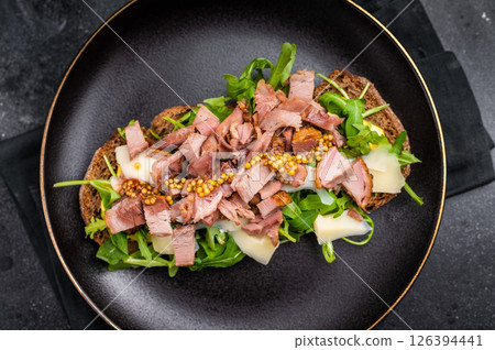 Toast with duck breast meat, foie gra, arugula and cheese on plate. black background. top view Toast with duck breast meat, foie gra, arugula and cheese on plate. black background. top view 126394441