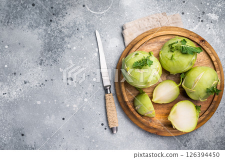 Raw kohlrabi sliced on pieces on wooden tray. grey backround. top view Raw kohlrabi sliced on pieces on wooden tray. grey backround. top view 126394450