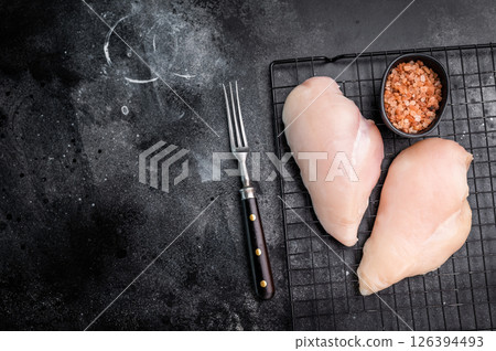 Fresh chicken breasts, beautifully displayed, showcasing their tender texture. Perfect for marinating and cooking your favorite dishes. black background. top view Fresh chicken breasts, beautifully displayed, showcasing their tender texture. Perfect for marinating and cooking your favorite dishes. black background. top view 126394493