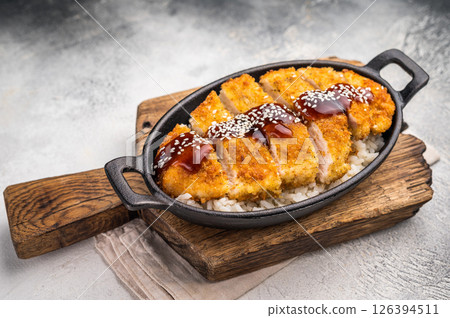 Katsu Crispy cutlet, perfectly breaded and golden brown, served with a side of rice and tangy sauce. A delicious Japanese classic that's hard to resist. grey background. top view Katsu Crispy cutlet, perfectly breaded and golden brown, served with a side of rice and tangy sauce. A delicious Japanese classic that's hard to resist. grey background. top view 126394511