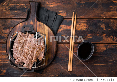 Flavorful yakiniku with juicy wagyu beef slices cooked right at the table. wooden background. top view 126394513