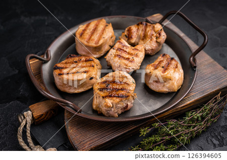 Flavorful grilled pork tenderloin cutlets, expertly cooked to perfection, promising a delicious dining experience. black background. top view Flavorful grilled pork tenderloin cutlets, expertly cooked to perfection, promising a delicious dining experience. black background. top view 126394605