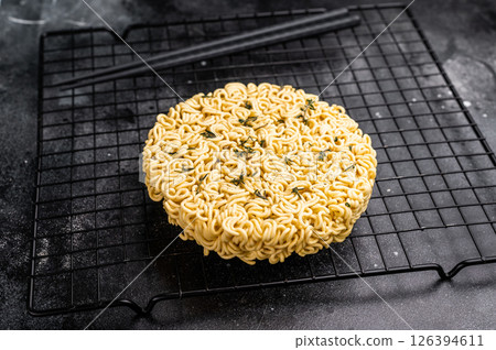 Raw instant ramen noodles, perfectly twisted and ready to be boiled for a delicious homemade soup. black background. top view 126394611