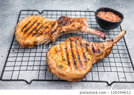 Juicy grilled pork Tomahawk chop, perfectly seared and bursting with flavor, ideal for a hearty feast. grey background. top view 126394612