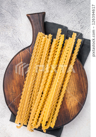 Delicate raw mafaldine pasta noodles, perfect for tossing with fresh ingredients and savory sauces. white background. top view Delicate raw mafaldine pasta noodles, perfect for tossing with fresh ingredients and savory sauces. white background. top view 126394617